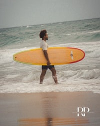 a man carrying a surfboard on the beach