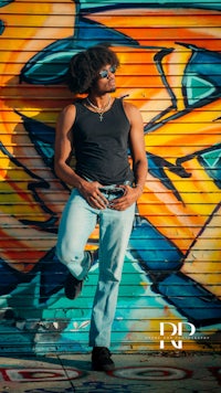 a man leaning against a graffiti wall